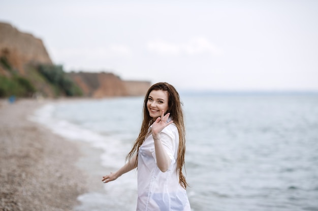 Mujer en ropa blanca refrescante a la orilla del mar.