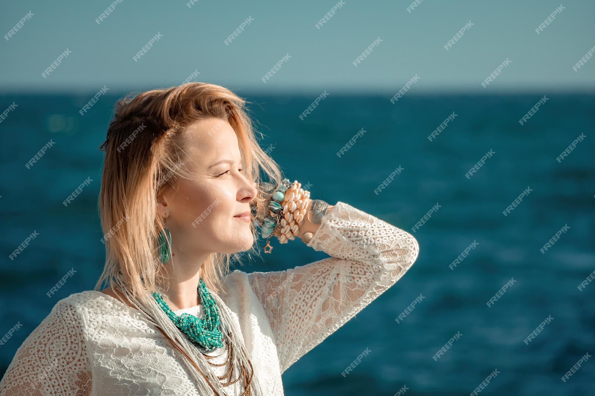 Mujer con ropa bohemia en la playa al atardecer boho para un en el resort de mediana edad | Foto Premium