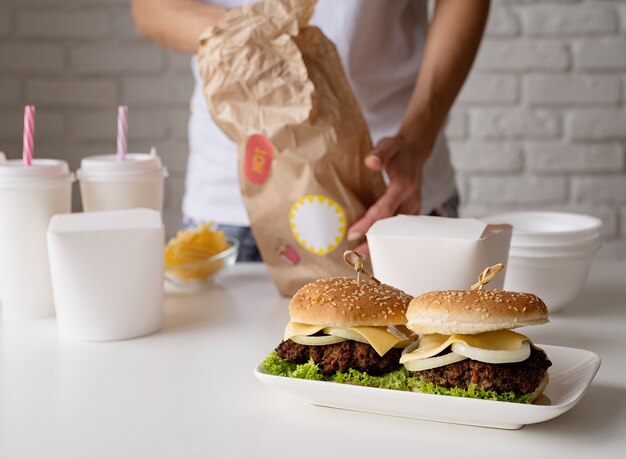 Mujer en ropa de casa desembalaje de alimentos entrega a domicilio ingenio hamburguesas cajas de fideos y bebidas