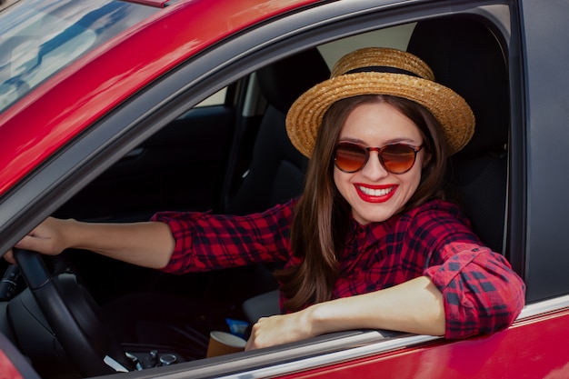 Mujer en ropa casual sonriendo mientras conduce un automóvil