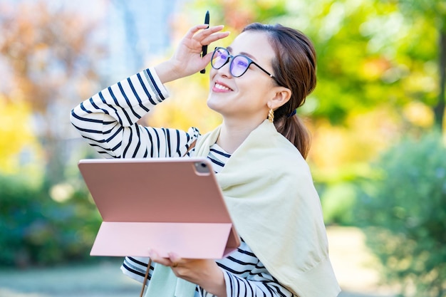 Mujer en ropa casual con un tablet PC al aire libre