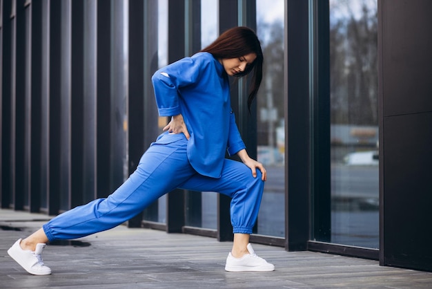 Mujer en ropa deportiva azul que se extiende fuera de la calle