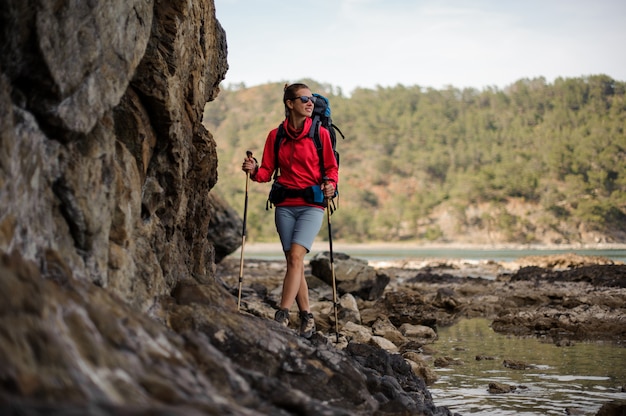 Mujer en ropa deportiva caminando sobre la roca con mochila de senderismo