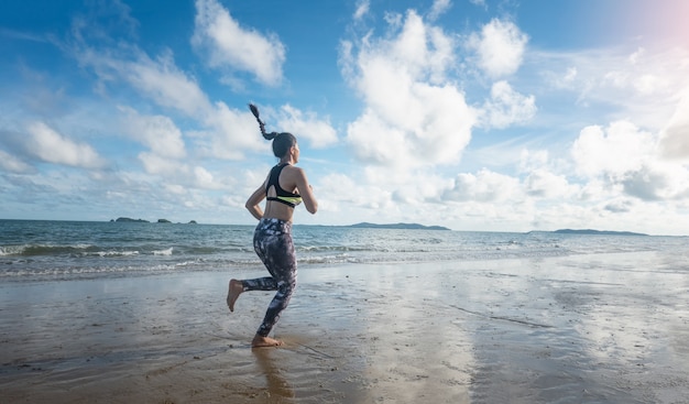 Mujer en ropa deportiva para correr en la playa en la mañana.