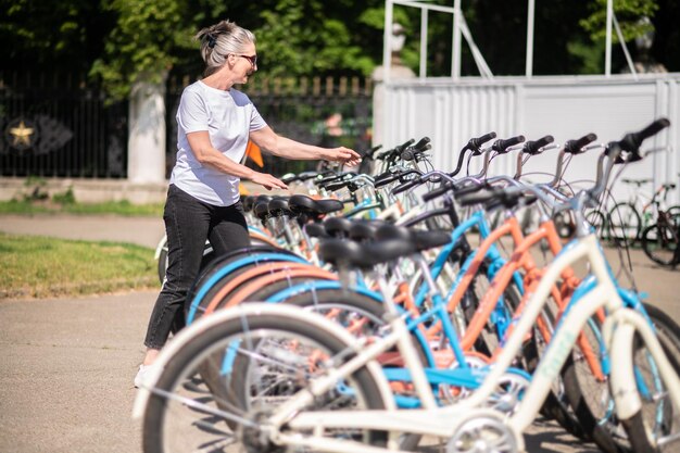 Una mujer en ropa deportiva eligiendo una bicicleta para alquilar