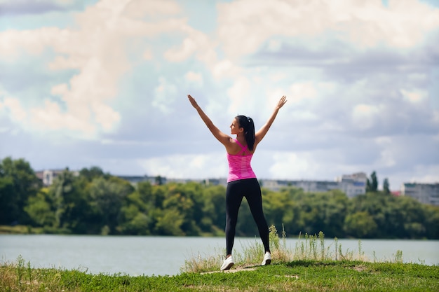 Mujer en ropa deportiva está practicando deportes en un lago en la ciudad