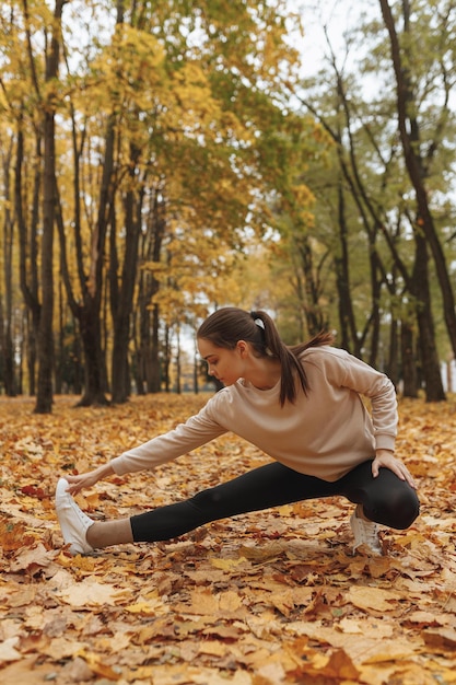 mujer en ropa deportiva estirando las piernas y haciendo ejercicio de estocada lateral mientras hace ejercicio físico