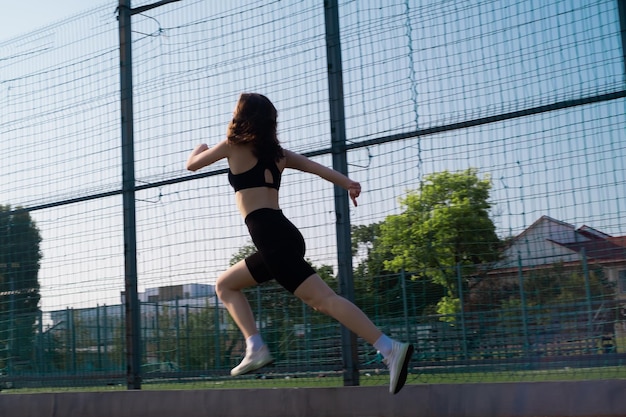 Una mujer con ropa deportiva hace ejercicio en un estadio deportivo Una mujer en forma hace jogging al aire libre