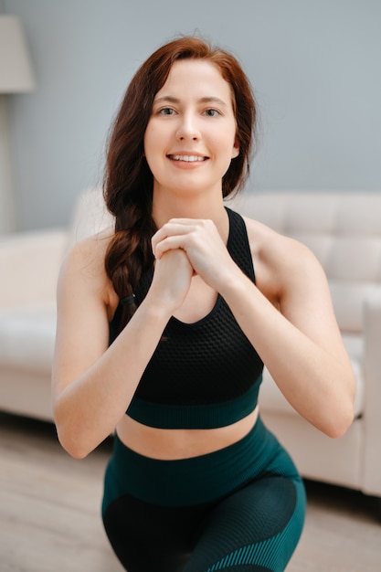 Mujer en ropa deportiva hace yoga en casa para estirar tendonesconcepto de fitness