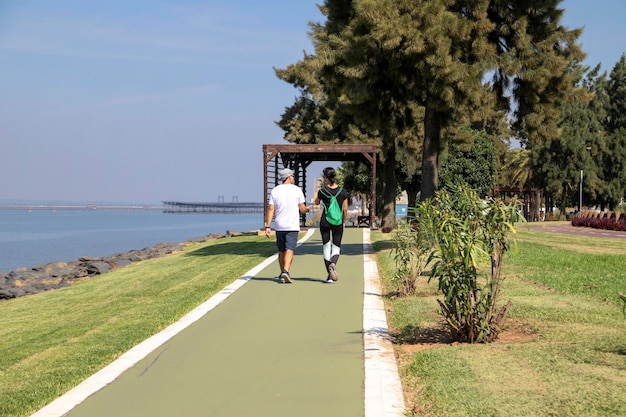 Mujer con ropa deportiva y hombre con ropa deportiva, caminando por la orilla del río. vista desde atrás