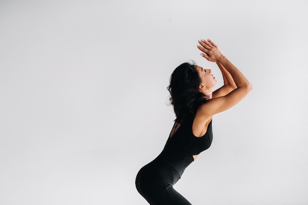 Una mujer con ropa deportiva negra participa en la meditación kali dinámica en la sala de yoga