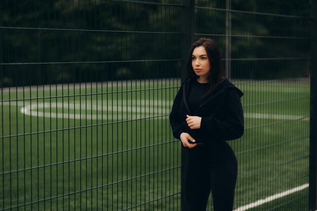 Foto una mujer con ropa deportiva oscura cerca de un campo de fútbol