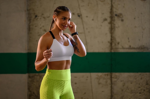 Mujer en ropa deportiva poniéndose airpods en los oídos antes de entrenar