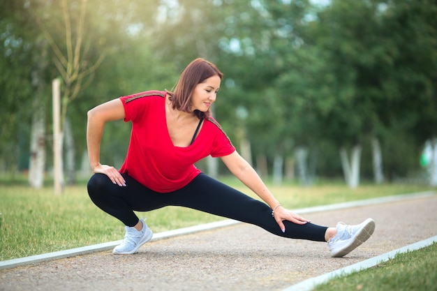 Mujer en ropa deportiva que se extiende antes de trotar en el parque