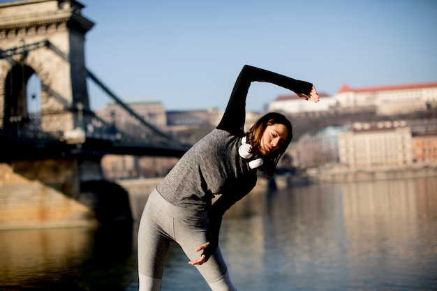 Mujer en ropa deportiva que se extiende en el paseo del río Danubio en Budapest