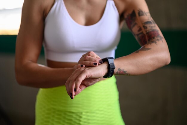 Mujer en ropa deportiva revisa el estado físico y el seguimiento de la salud en su reloj inteligente después del entrenamiento