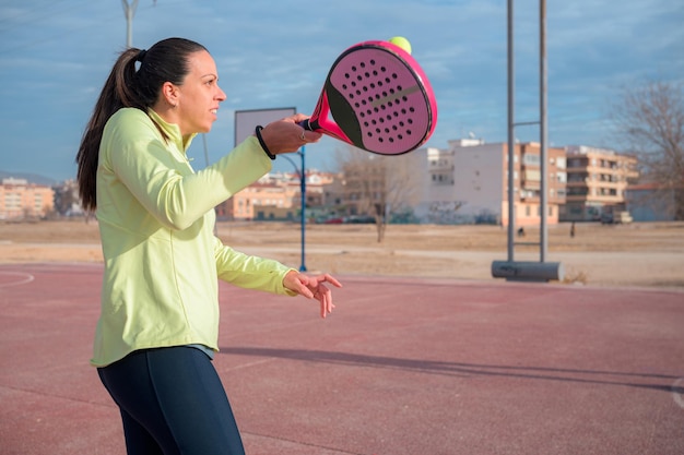 Mujer con ropa deportiva sostiene una raqueta y juega al pádel