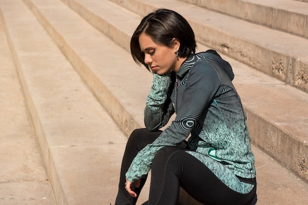 Mujer en ropa deportiva triste sentada en las escaleras deprimida voluntad débil Concepto de estilo de vida activo enfoque selectivo