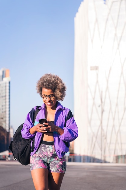 Foto mujer con ropa deportiva usando un móvil en la ciudad