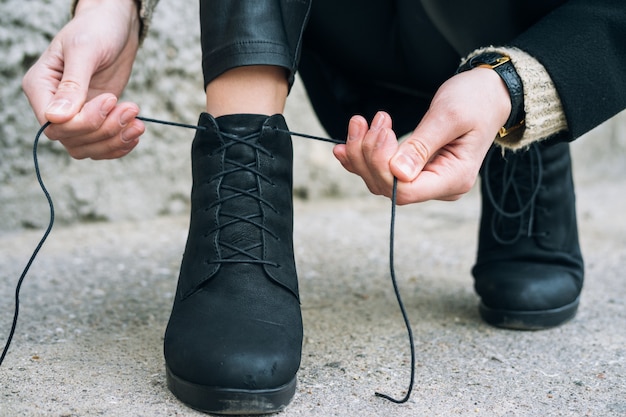 La mujer en la ropa elegante que ata los cordones en los zapatos se cierra para arriba