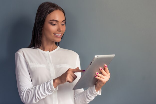 Mujer en ropa formal está utilizando una tableta digital.