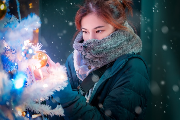 Mujer en ropa de invierno cerca de un árbol de Navidad