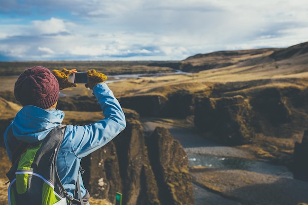 Mujer con ropa de invierno tomando fotos en Islandia