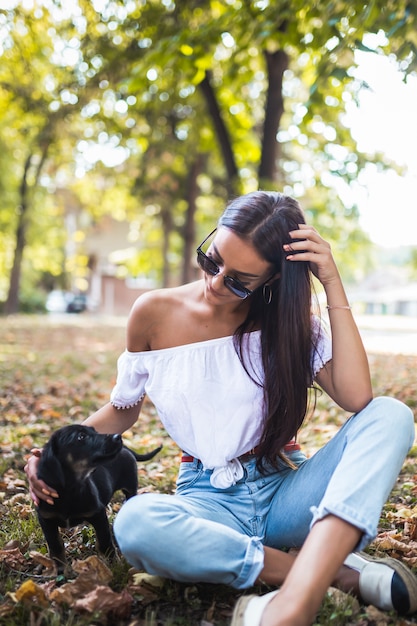 Una mujer en ropa de otoño abrazando perro en la naturaleza