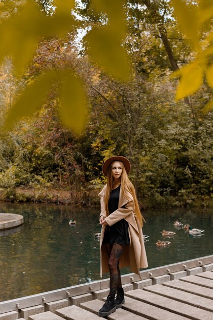 Una mujer en ropa de otoño en el puente del parque de la ciudad. tendencias de otoño