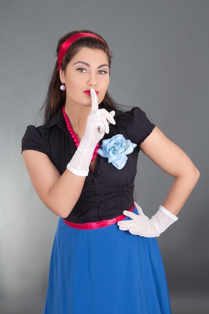 Mujer en ropa retro con el dedo en labios sobre gris | Foto Premium