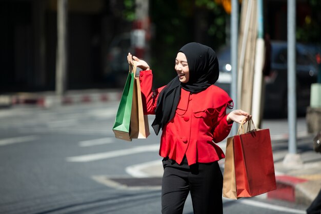 Mujer en ropa roja con bolsas de compras al aire libre atanding