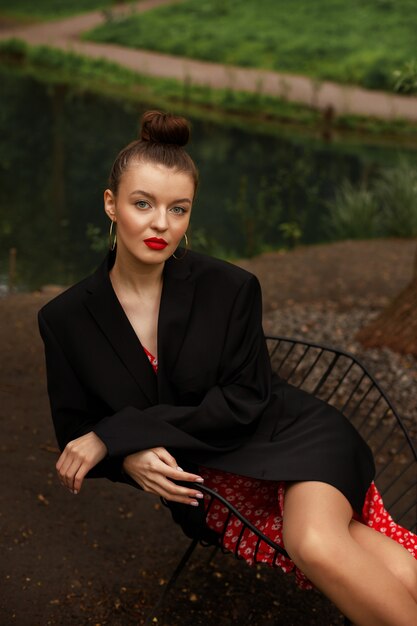 Mujer en ropa romántica en el parque de verano en un paseo. modelo en chaqueta negra y vestido rojo.