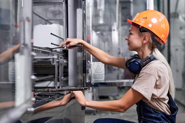 Mujer en ropa de trabajo en la fábrica de reparación de máquinas robóticas con herramienta de llave