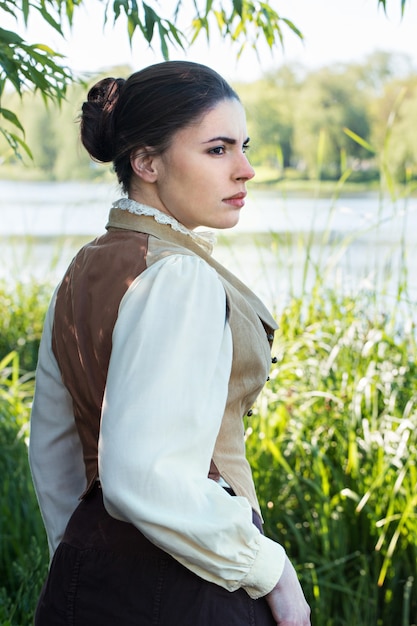 Mujer en ropa vintage en la orilla del río