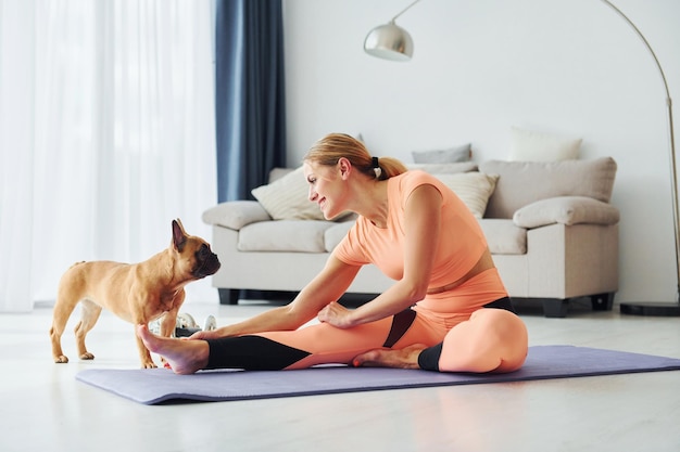 Mujer en ropa de yoga con perro pug está en casa durante el día