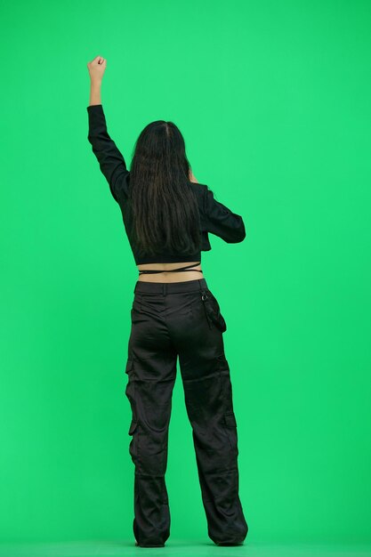 Una mujer con ropas negras sobre un fondo verde en gritos de altura completa
