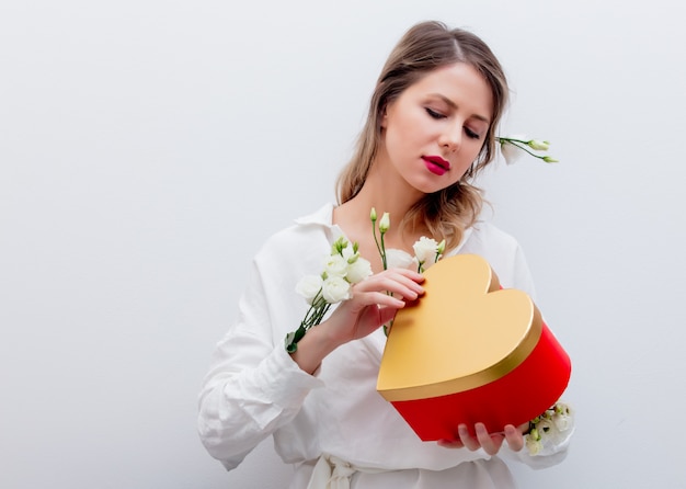 mujer con rosas blancas con una caja de regalo de forma de corazón.