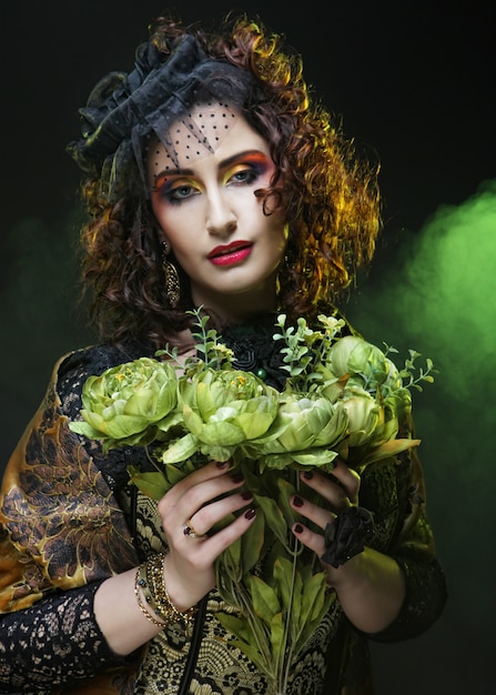 Mujer con rostro brigt sosteniendo grandes flores verdes