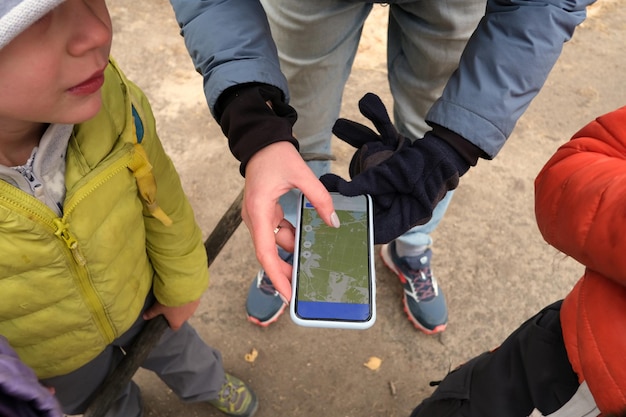 Mujer sin rostro que muestra el mapa en el teléfono inteligente para niños anónimos