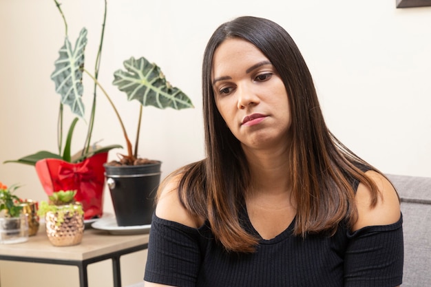 Mujer con rostro triste y sentada en el sofá.