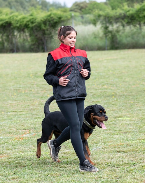 Mujer y rottweiler en la naturaleza.