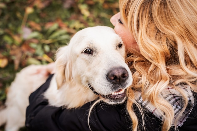 Una mujer rubia abrazando a su perro perdiguero en el parque