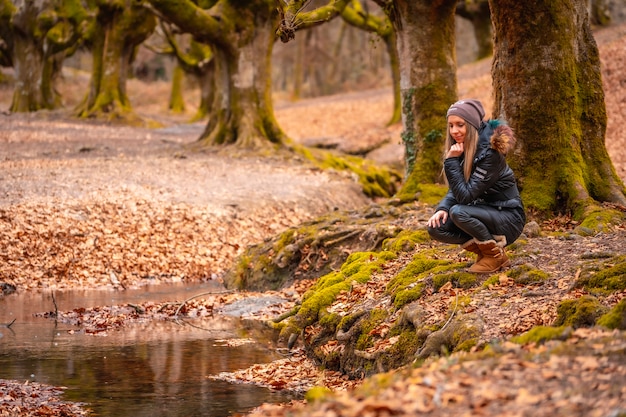 mujer rubia con un abrigo largo en un bosque