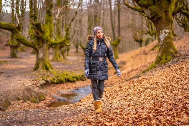 mujer rubia con un abrigo largo en un bosque