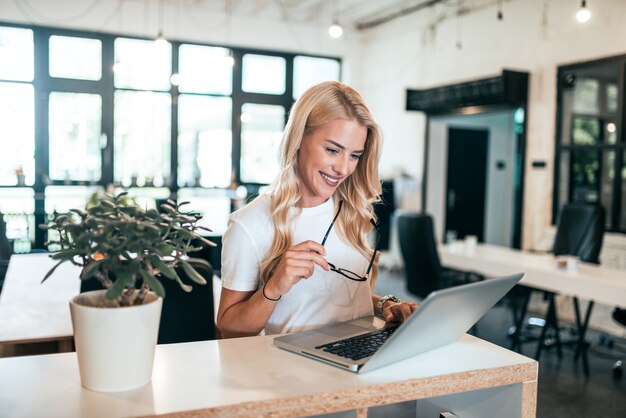 Mujer rubia acertada que usa la computadora portátil.