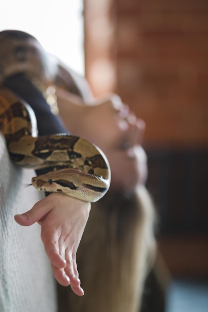 Mujer rubia acostada boca abajo en la cama con una serpiente de cerca