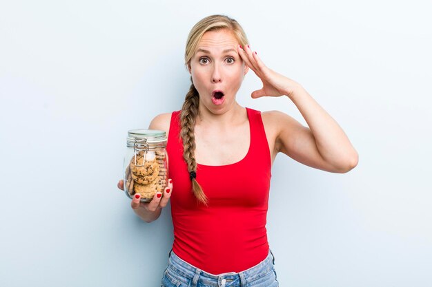 Mujer rubia adulta joven con botella de galletas caseras