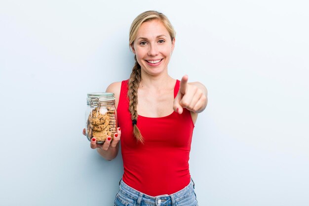 Mujer rubia adulta joven con botella de galletas caseras