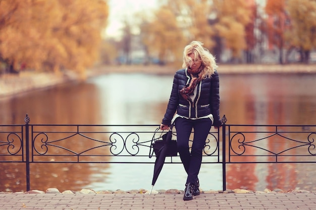 mujer rubia adulta en el parque de otoño