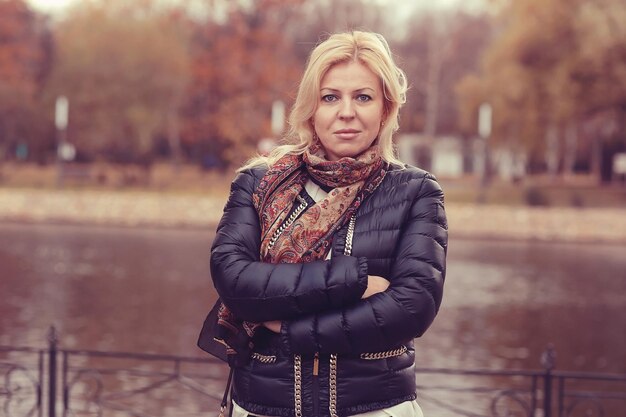 mujer rubia adulta en el parque de otoño